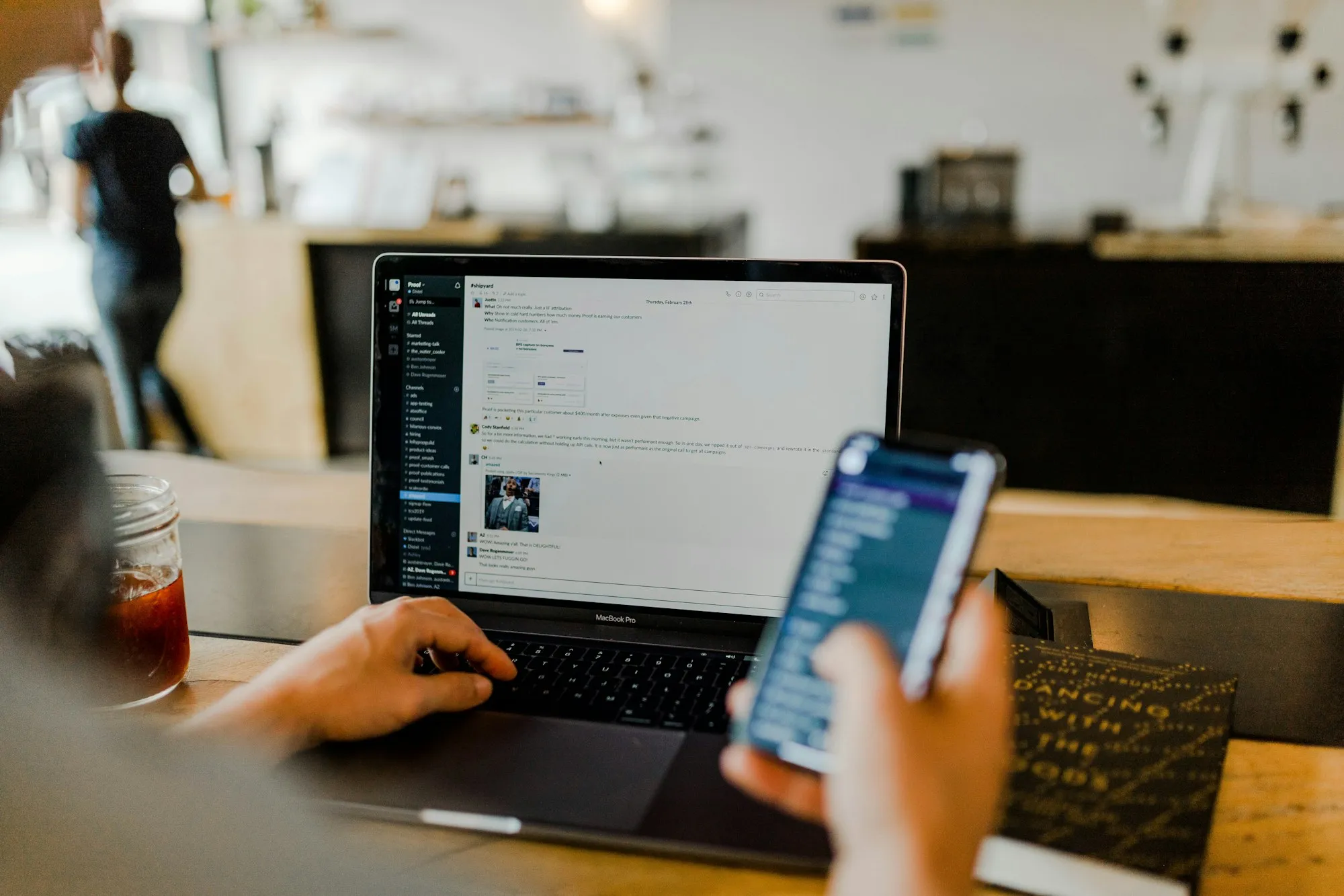 Người dùng làm việc với laptop và điện thoại tại quán cà phê